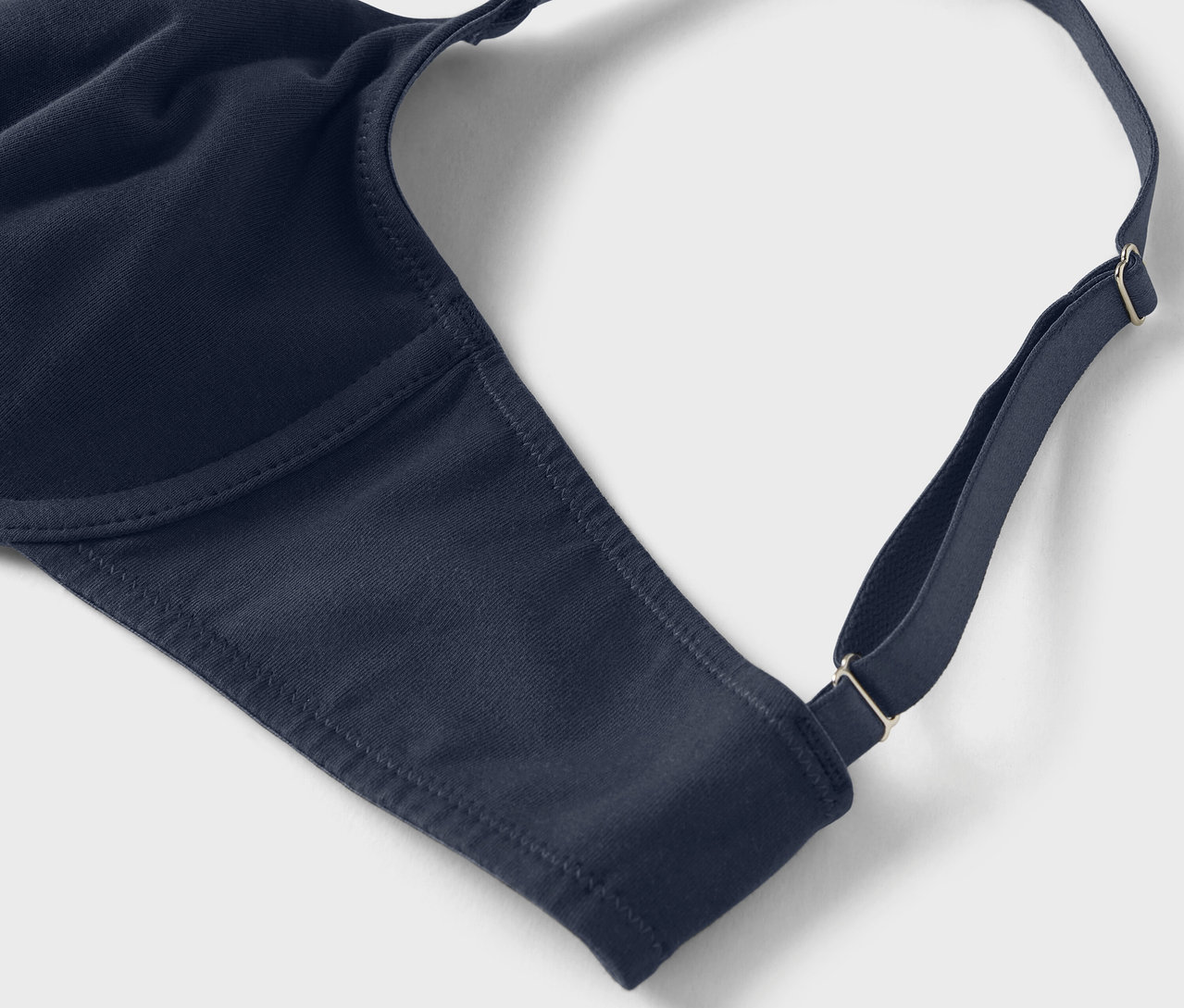 Detailaufnahme eines marineblauen BHs mit verstellbaren Trägern auf hellem Hintergrund.