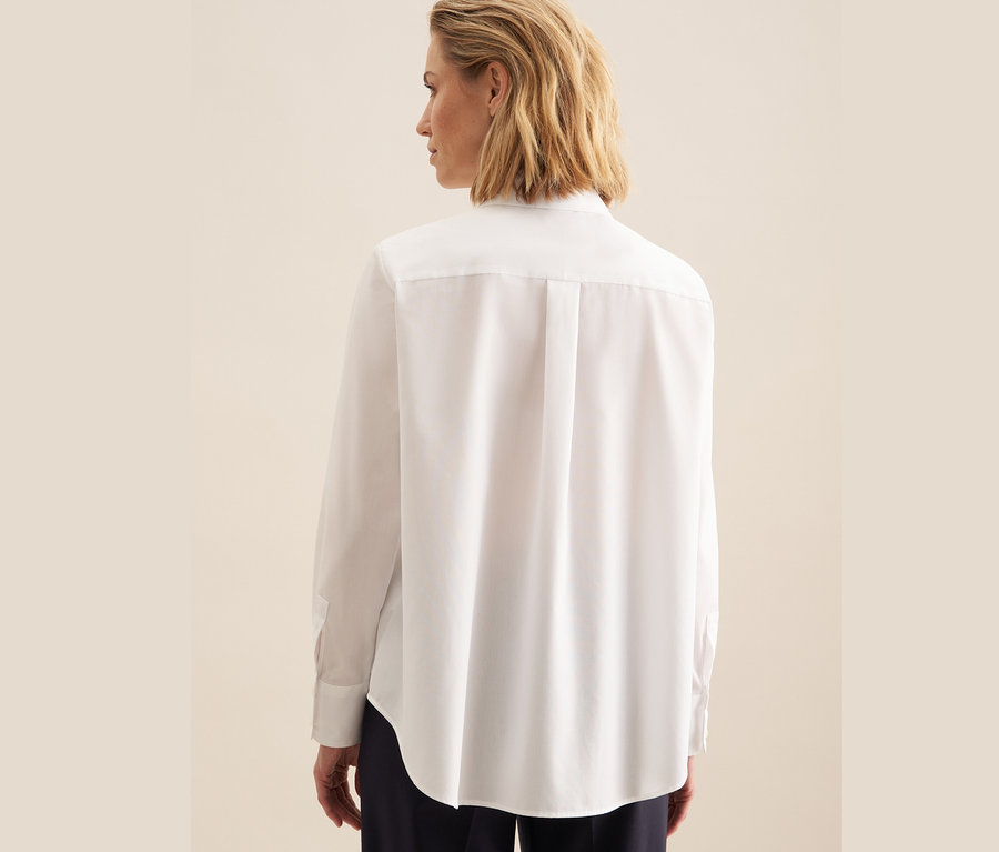 Rückansicht einer Frau in einer weißen, bügelfreien Bluse von Seidensticker.
