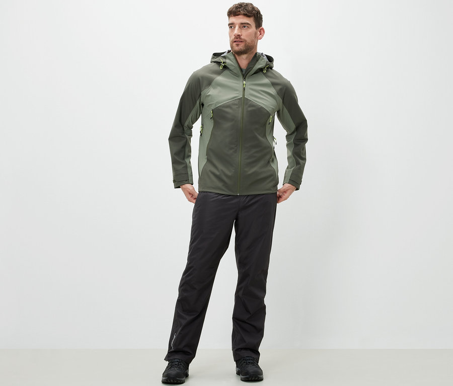 Mann steht und trägt eine High-Tech-Regenhose und eine Jacke.