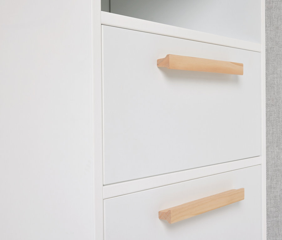 Nahaufnahme eines weißen Schranks mit zwei Schubladen und hellbraunen Holzgriffen.