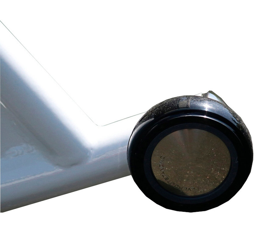 Nahaufnahme eines schwarzen, runden Möbelbeins mit einer braunen Mitte, das an einem weißen Möbelstück befestigt ist.