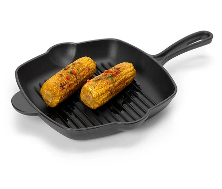 Zwei Maiskolben mit Gewürzen liegen in einer schwarzen Grillpfanne.