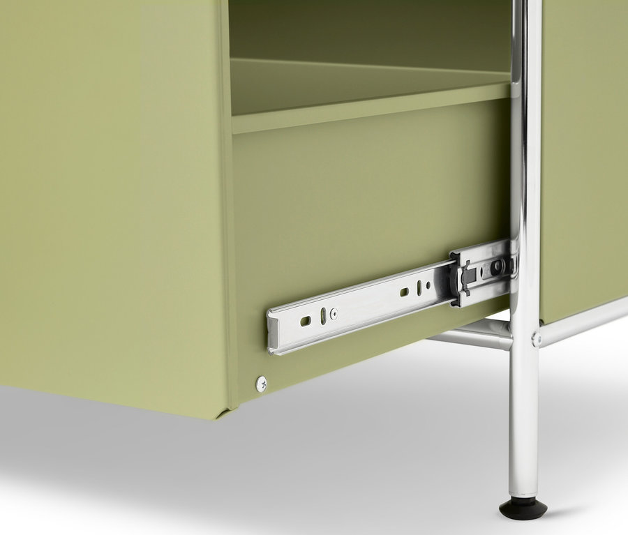 Nahaufnahme eines hellgrünen Schranks mit silbernen Beinen, wobei die Schublade teilweise geöffnet ist.