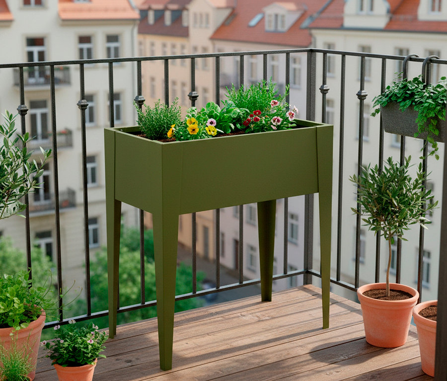 Auf einem Balkon steht ein erhöhter, olivgrüner Pflanzkasten mit Blumen und Kräutern, umgeben von Topfpflanzen.