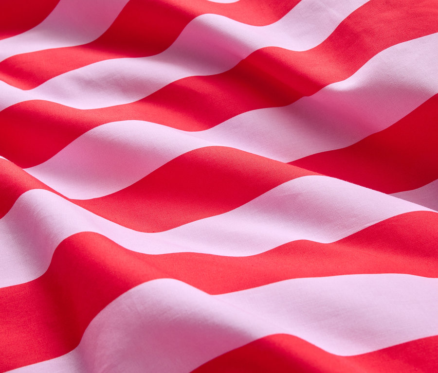 Nahaufnahme eines Stoffes mit roten und weißen Streifen, der wellenförmig drapiert ist.