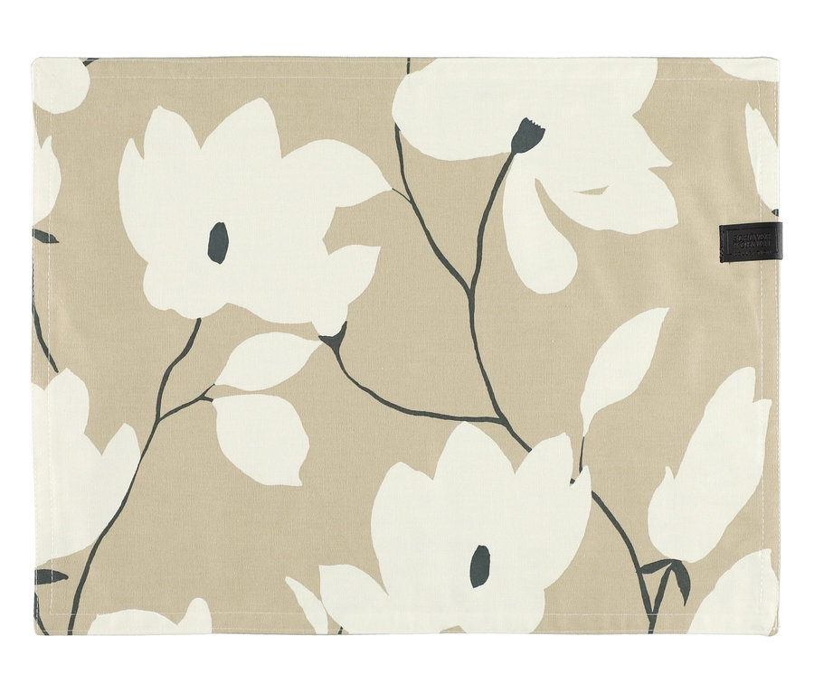 Ein sandfarbenes Tischset der SCHÖNER WOHNEN-Kollektion mit weißem Blumenmuster, dunklen Stielen und Blättern. Oben rechts ist ein kleines schwarzes Etikett zu sehen.