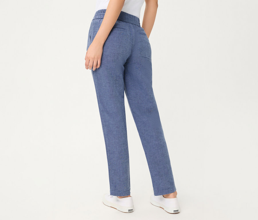 Eine Person von hinten, die eine blaue, verkürzte Olsen Jeans und weiße Sneaker trägt.