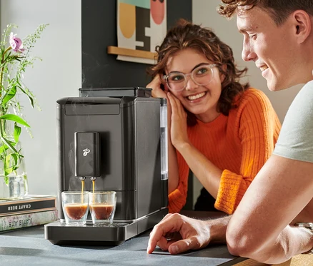 Zwei Personen beobachten, wie Kaffee aus einem »Esperto2 Caffè« Kaffeevollautomaten in zwei Gläser gefüllt wird.