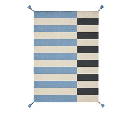Rechteckiger Benuta Kinderteppich »Janou« in Blau mit Streifenmuster. Die linke Seite zeigt horizontale hellblaue und cremefarbene Streifen, die rechte Seite vertikale dunkelblaue und cremefarbene Streifen. Blaue Quasten an jeder Ecke.