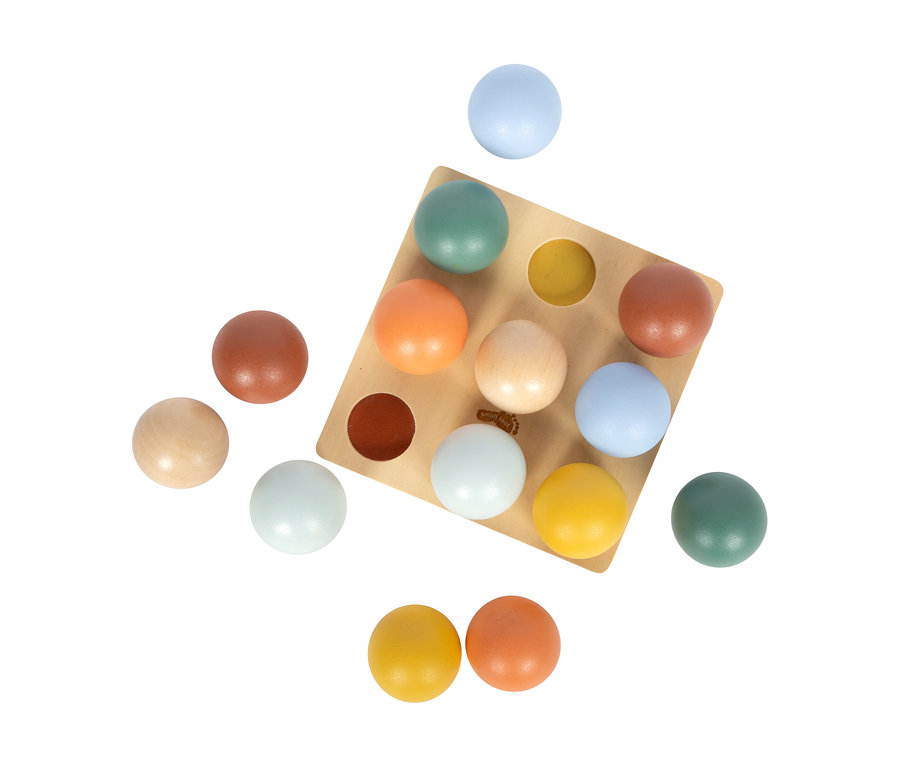 Ein quadratisches, helles Holzbrett des small foot Montessori-Bundle 2 mit 9 runden Vertiefungen, gefüllt mit bunten Holzkugeln in Blau, Grün, Orange, Gelb und Braun. Einige Kugeln liegen daneben.