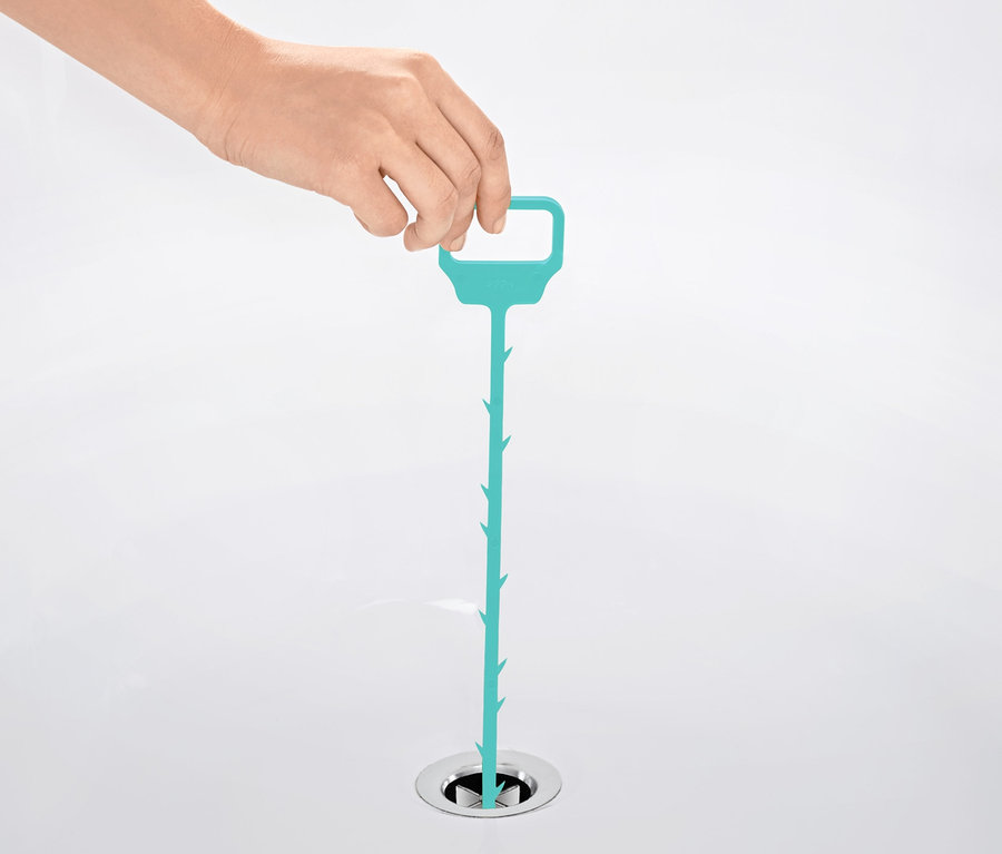 Eine Hand führt einen blauen Abflussreiniger in einen Abfluss ein.