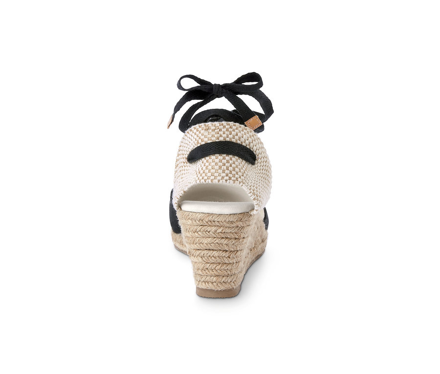 Detail der Rückseite einer Espadrilles mit Keilabsatz, die ein schwarzes Band und eine beige geflochtene Ferse hat.