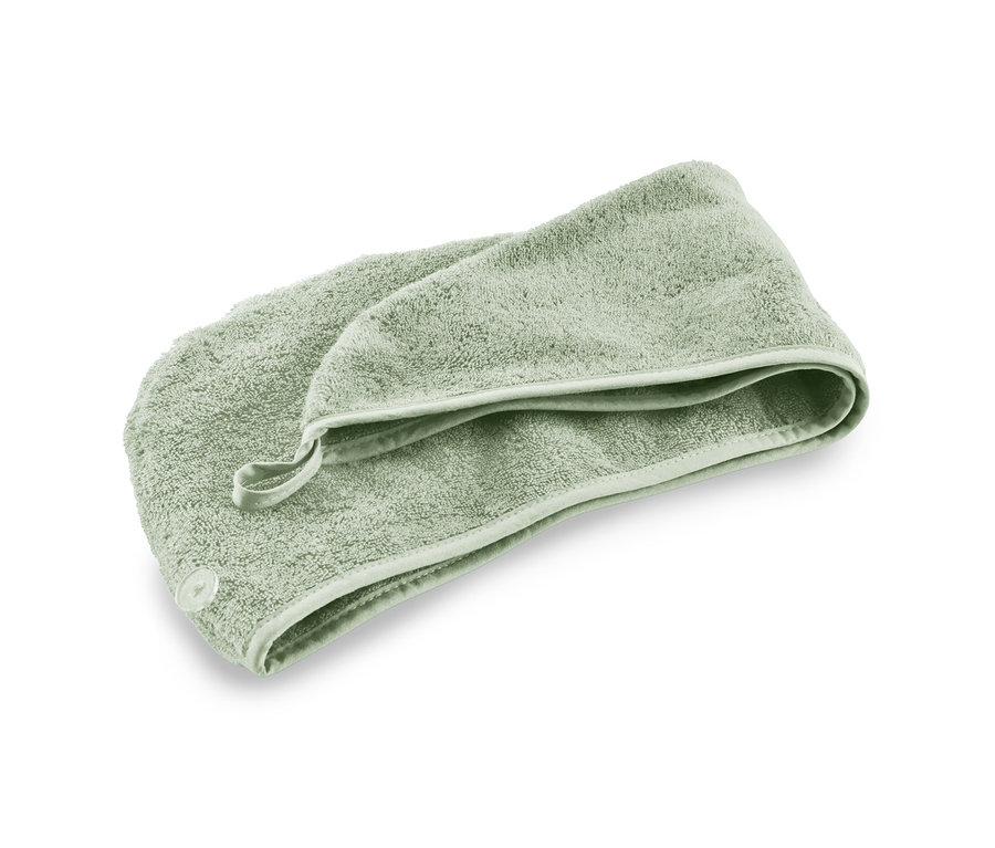 Ein grünes Turban-Handtuch liegt auf einem weißen Hintergrund.