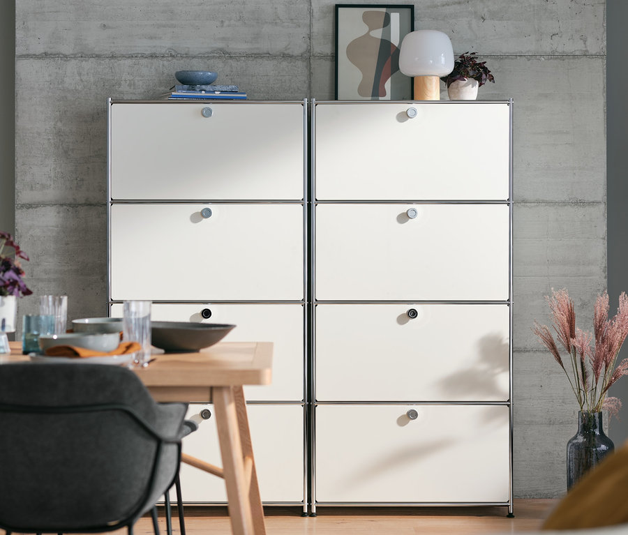 Zwei weiße Highboards Metall »CN3« mit 4 Klappenfächern stehen nebeneinander hinter einem Esstisch.