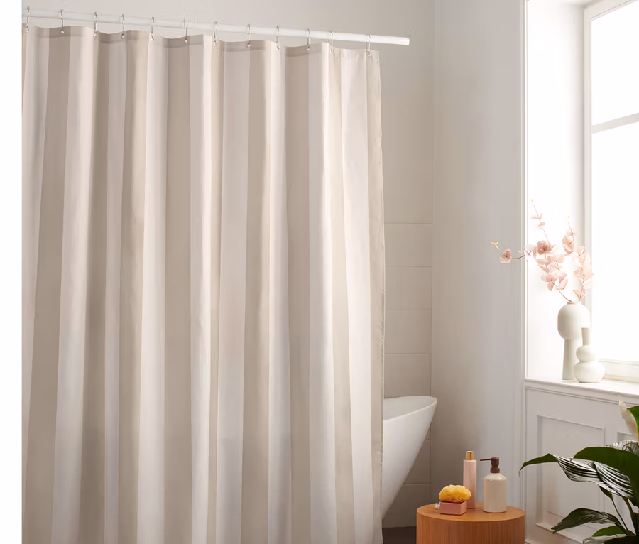 Beige-weißer Textil-Duschvorhang hängt im Badezimmer.
