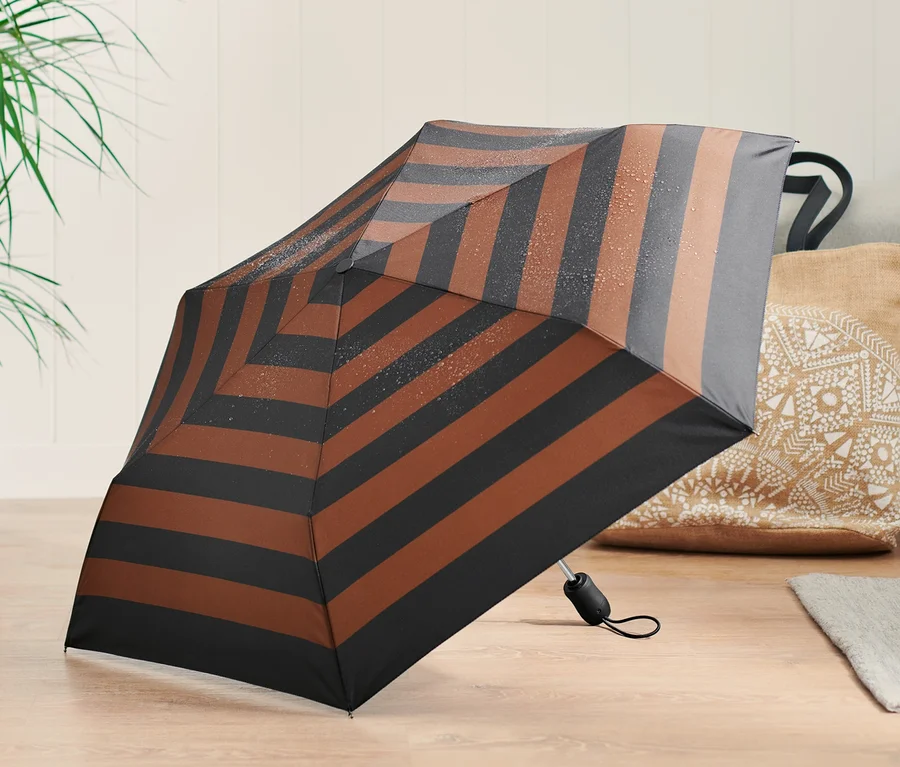 Geöffneter Automatik-Taschenschirm mit braunen und schwarzen Streifen auf einem Holzboden.