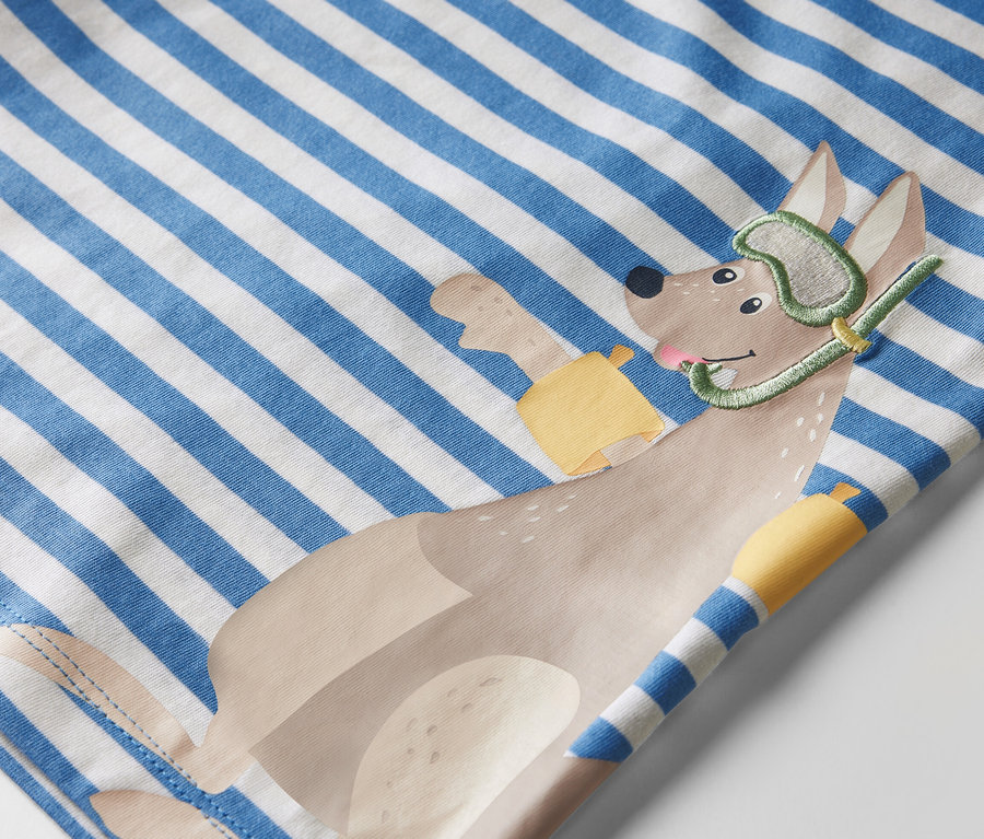 Detailansicht eines Kinder-T-Shirts mit blau-weißen Streifen und einer Applikation eines Hundes mit Taucherbrille und Schnorchel.