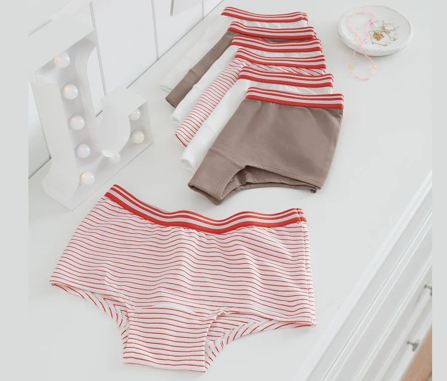 Auf einer weißen Kommode liegen 7 Kinder-Pantys.