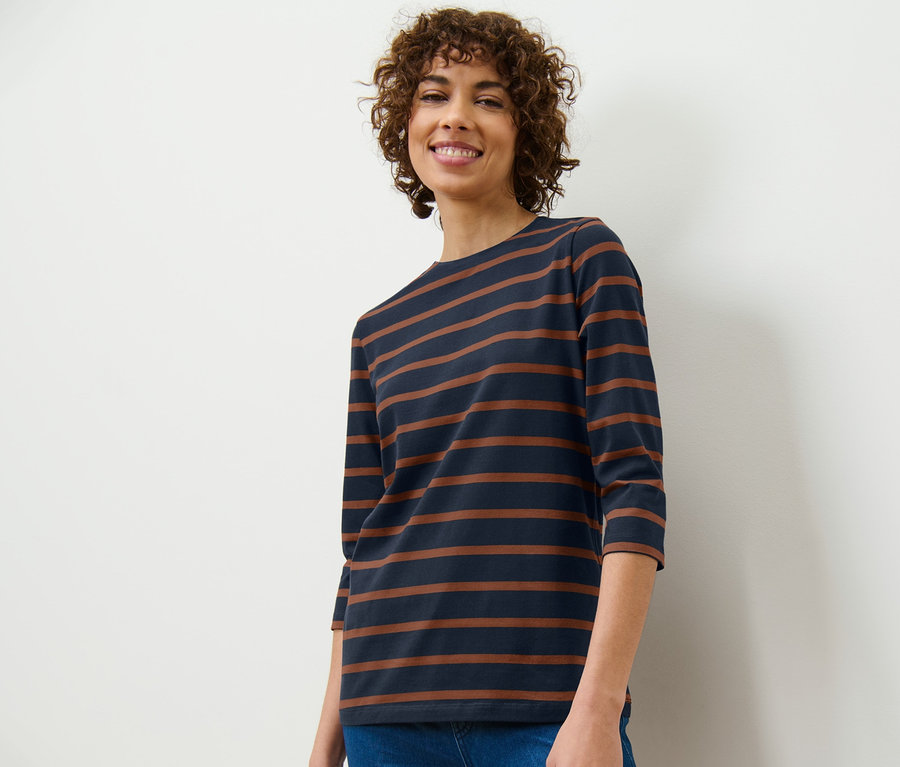 Frau trägt ein gestreiftes Shirt mit 3/4-Arm und Jeans.