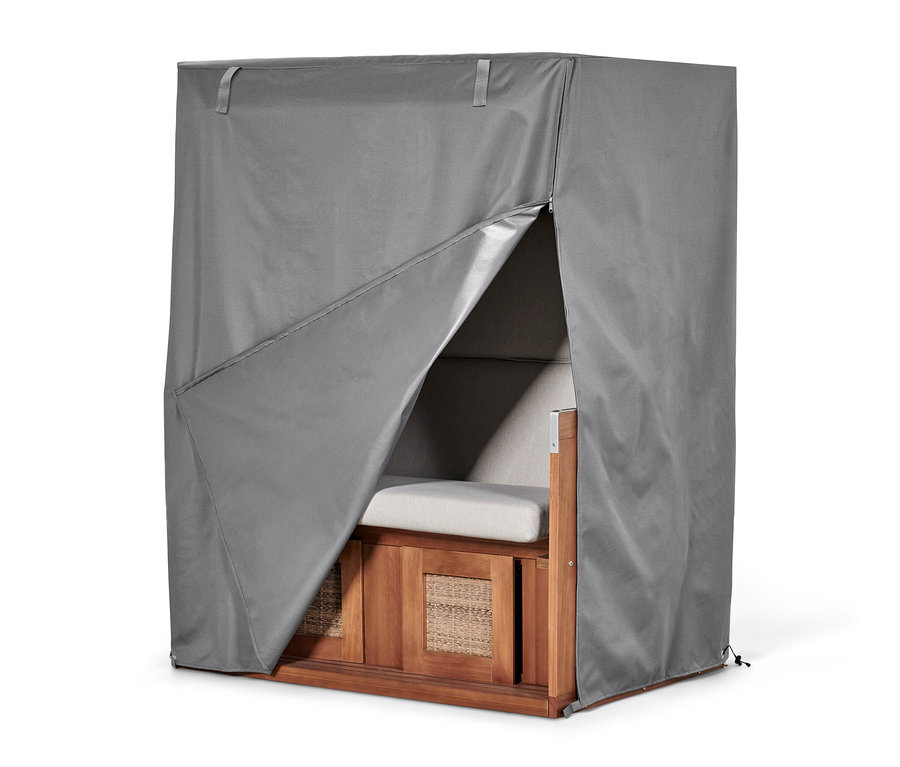 Ein Strandkorb ist mit einer grauen Premium-Abdeckhaube XXL abgedeckt, die teilweise geöffnet ist.