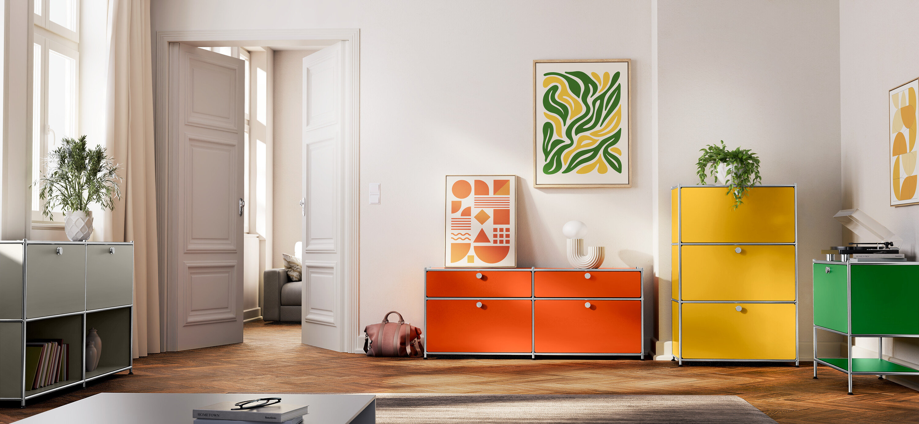 Wohnzimmer mit verschiedenfarbigen Metallkommoden, darunter ein orangefarbenes Sideboard »CN3« mit zwei Klappenfächern und zwei Schubladen, ein hellgraues Sideboard »CN3« mit zwei versetzbaren Klappenfächern, ein grünes Sideboard »CN3« mit einem Klappfach und eine gelbe Kommode »CN3« mit drei Klappenfächern.