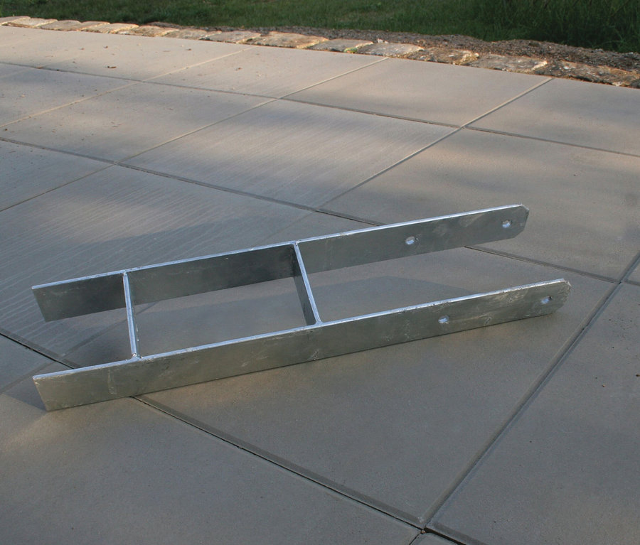 Ein silberner Metallrahmen liegt auf Betonpflaster.