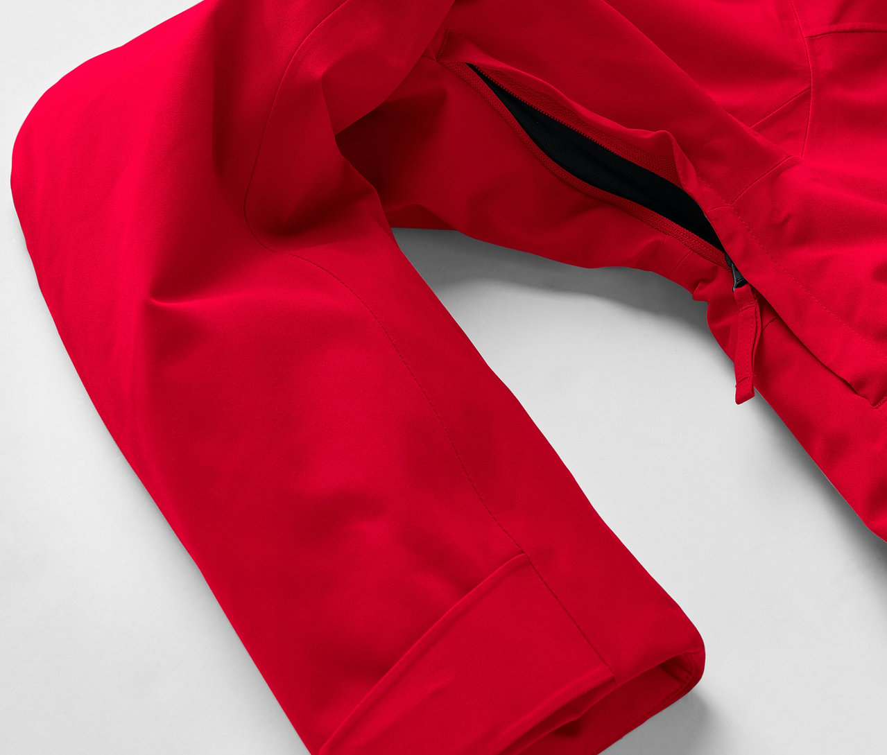 Detail einer roten Jacke mit Ärmel und Reißverschlusstasche.