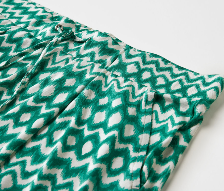 Detailansicht von 2 Jerseyshorts in Grün und Weiß mit Print und Kordelzug in der Taille.