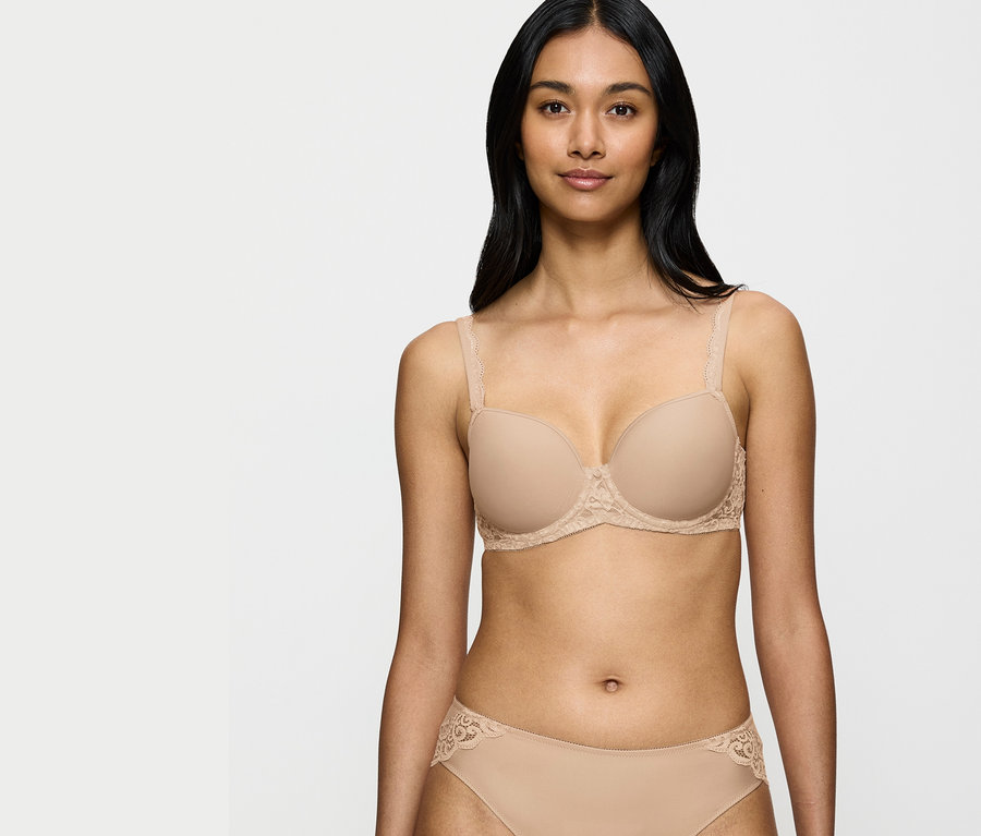 Frau trägt einen beigen BH und Höschen mit Spitzendetails.