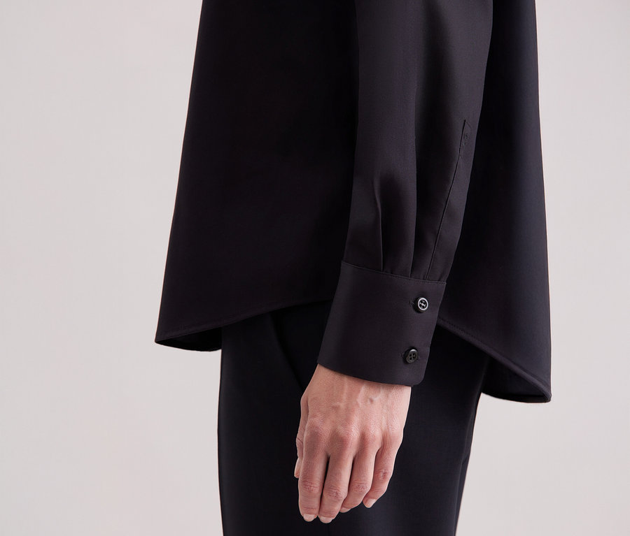 Nahaufnahme einer Frau, die eine schwarze Seidensticker Regular-Bluse trägt.