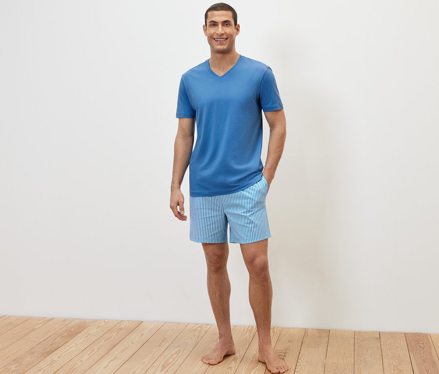 Mann posiert in einem Shorty-Pyjama-Set.
