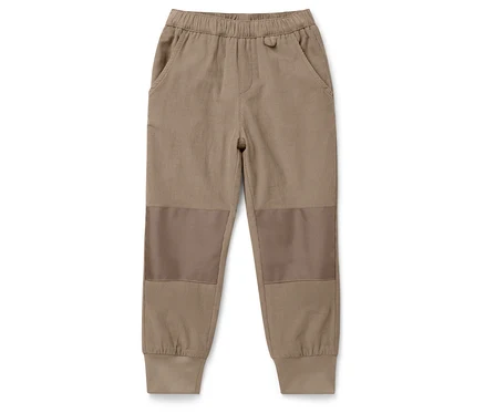 Braune Kinderhose mit Flicken auf den Knien, liegend auf einem weißen Hintergrund.