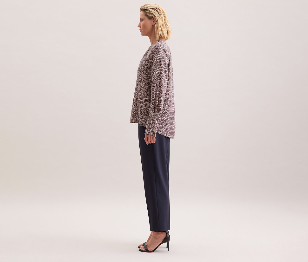 Frau trägt eine Seidensticker Tunika aus Viskose mit ecru-burgundy Alloverprint, kombiniert mit einer dunklen Hose und schwarzen High Heels.
