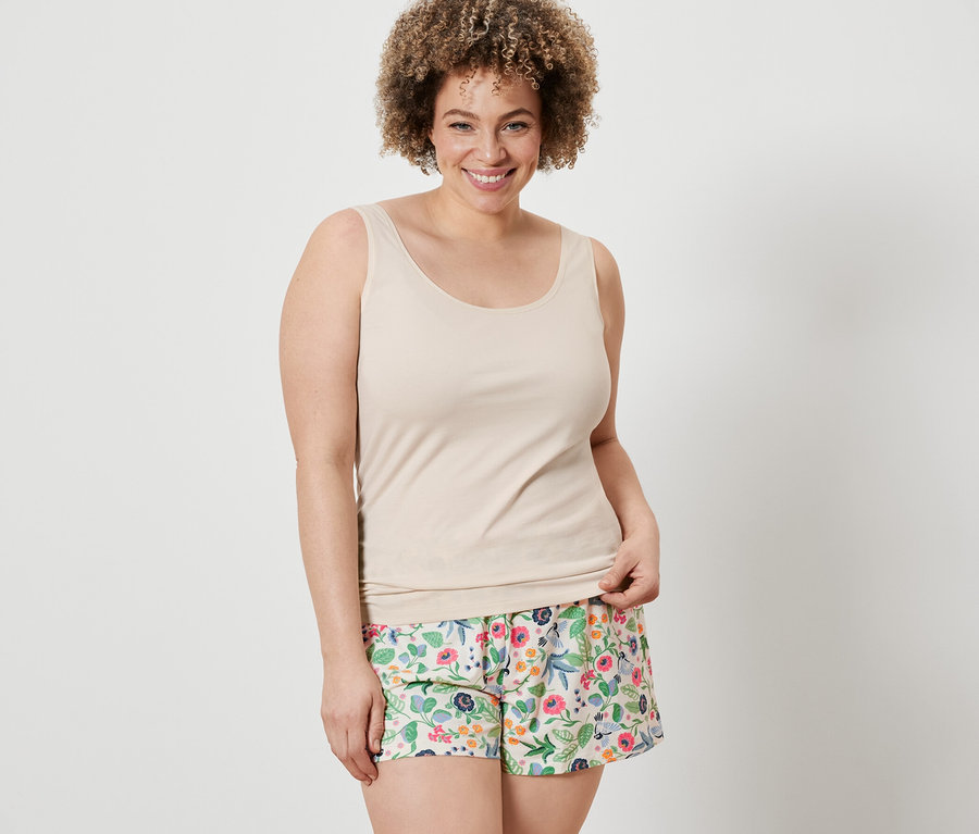 Frau trägt ein cremefarbenes Hemdchen und blumige Shorts von 2 Shorts und 2 Hemdchen.