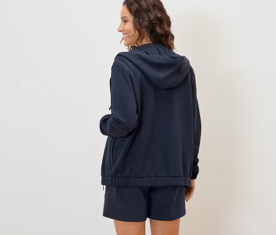 Frau von hinten trägt eine dunkelblaue Sweatjacke und Shorts.