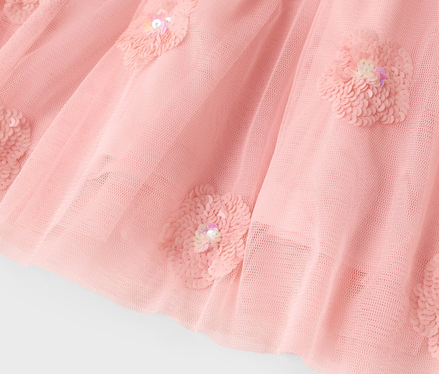 Nahaufnahme eines rosa Tüllrocks mit Paillettenblumenapplikationen.