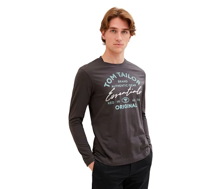Mann mit Tom Tailor Longsleeve mit Logo, Dark Shadow, mit Händen in den Hosentaschen.