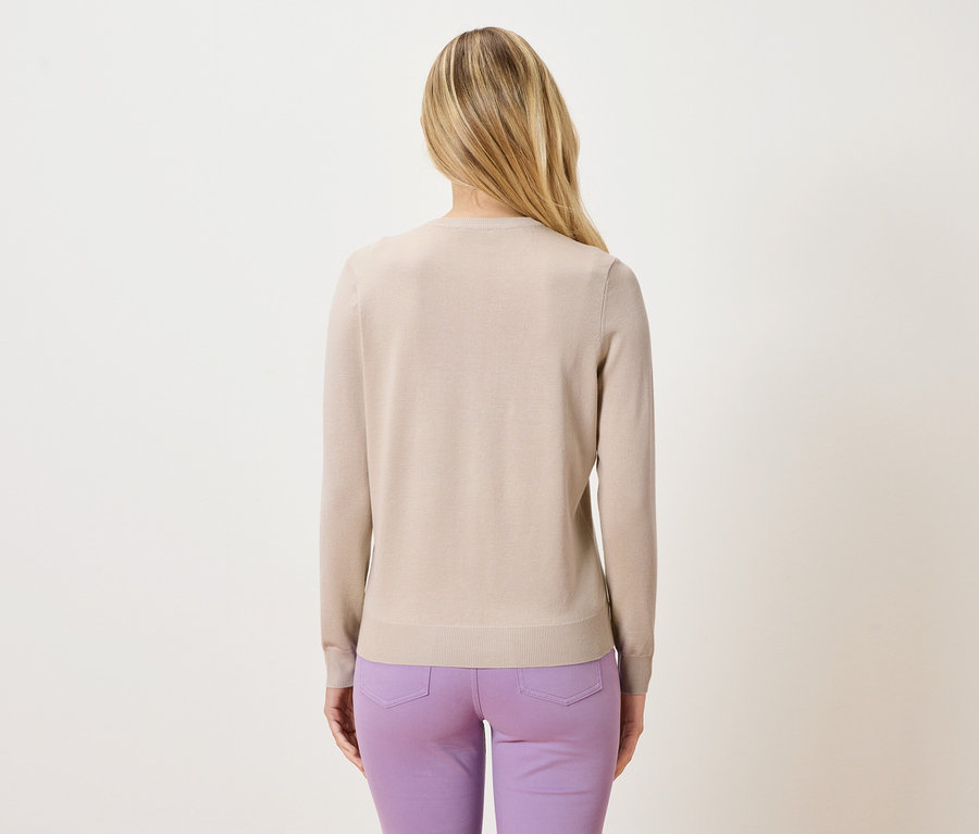 Rückansicht einer Frau mit blonden Haaren, die einen beige Pullover und eine lila Hose trägt.