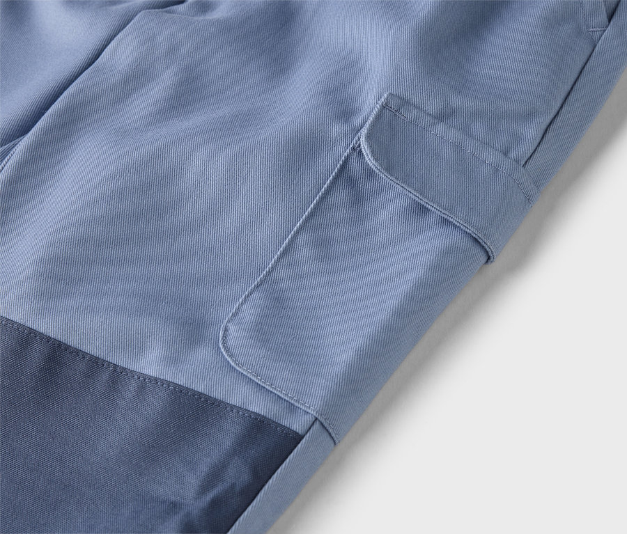 Nahaufnahme einer hellblauen Hose mit einer aufgesetzten Tasche am Bein und einem marineblauen Einsatz am unteren Bein.