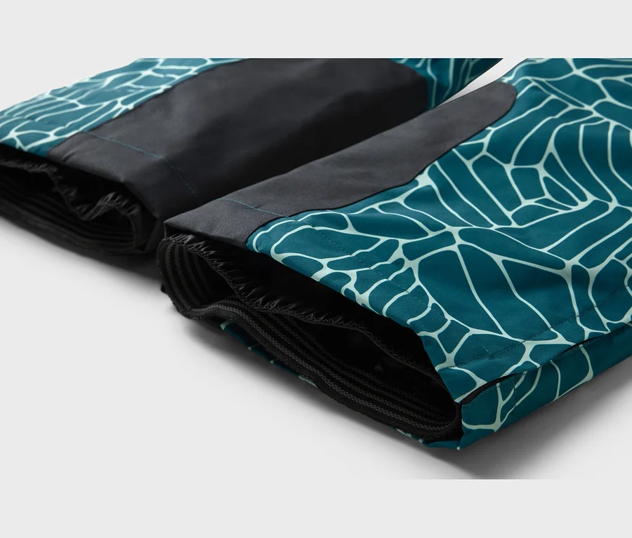 Zwei Hosenbeine in Türkis mit weißem geometrischem Muster und schwarzen Einsätzen, mit elastischen Bündchen am Saum.