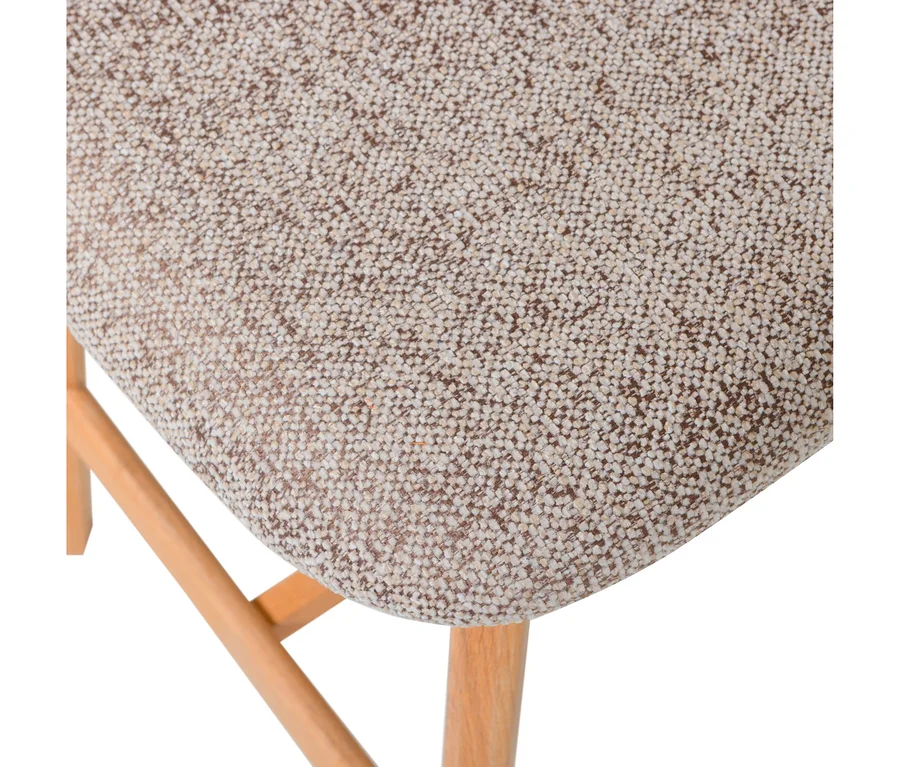 Nahaufnahme eines Stuhlsitzes, der mit gesprenkeltem beige-braunem Stoff bezogen ist, mit hellen Holzbeinen darunter.
