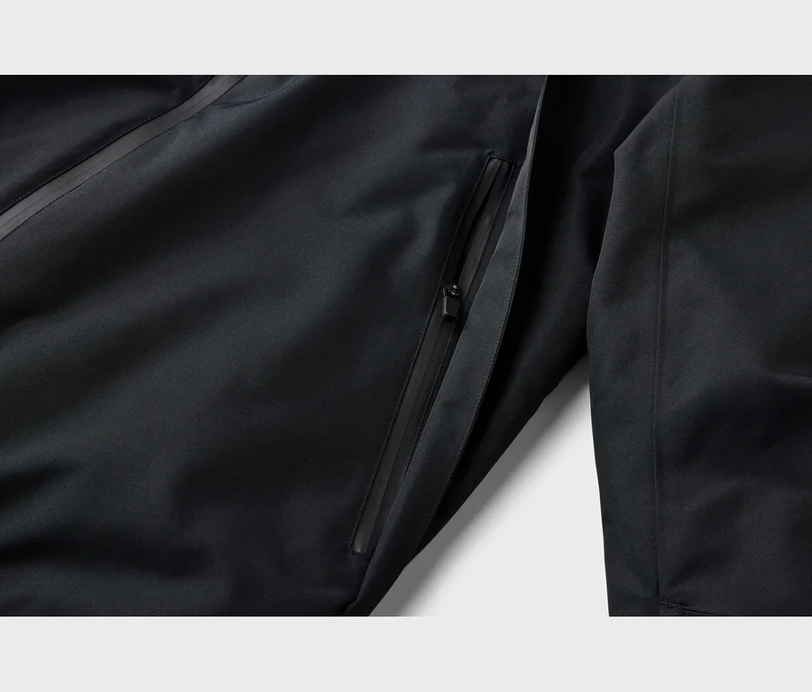 Nahaufnahme einer schwarzen Jacke mit einer teilweise geöffneten Reißverschlusstasche und einem schwarzen Reißverschlusszipper. Eine diagonale Naht verläuft oben links.