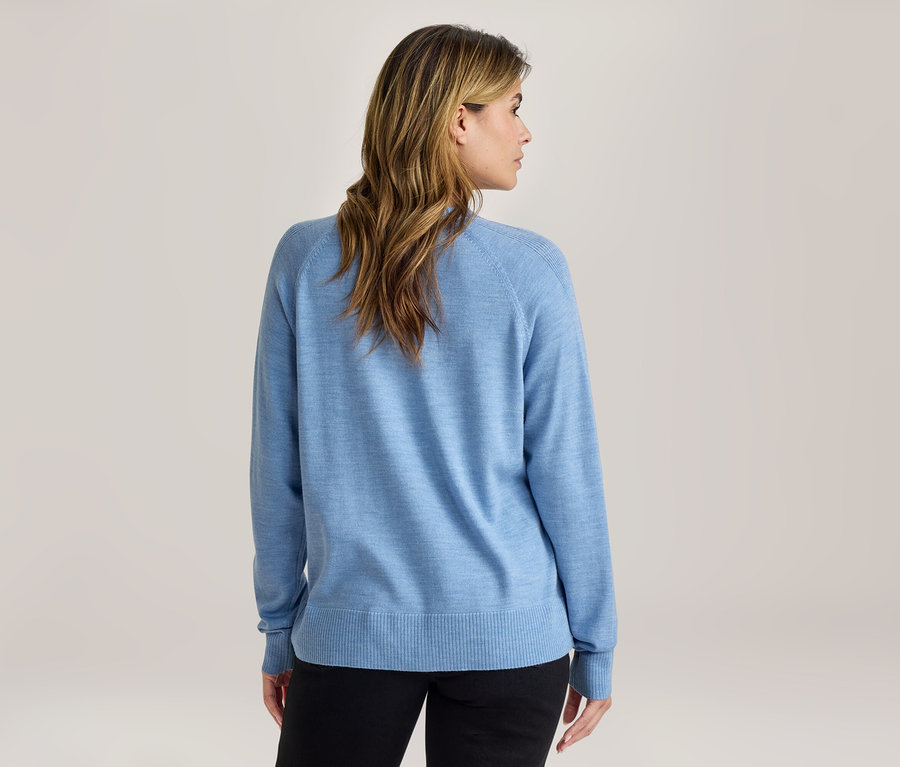 Frau von hinten, trägt einen hellblauen Pullover und schwarze Hose, der Kopf ist leicht zur Seite gedreht.