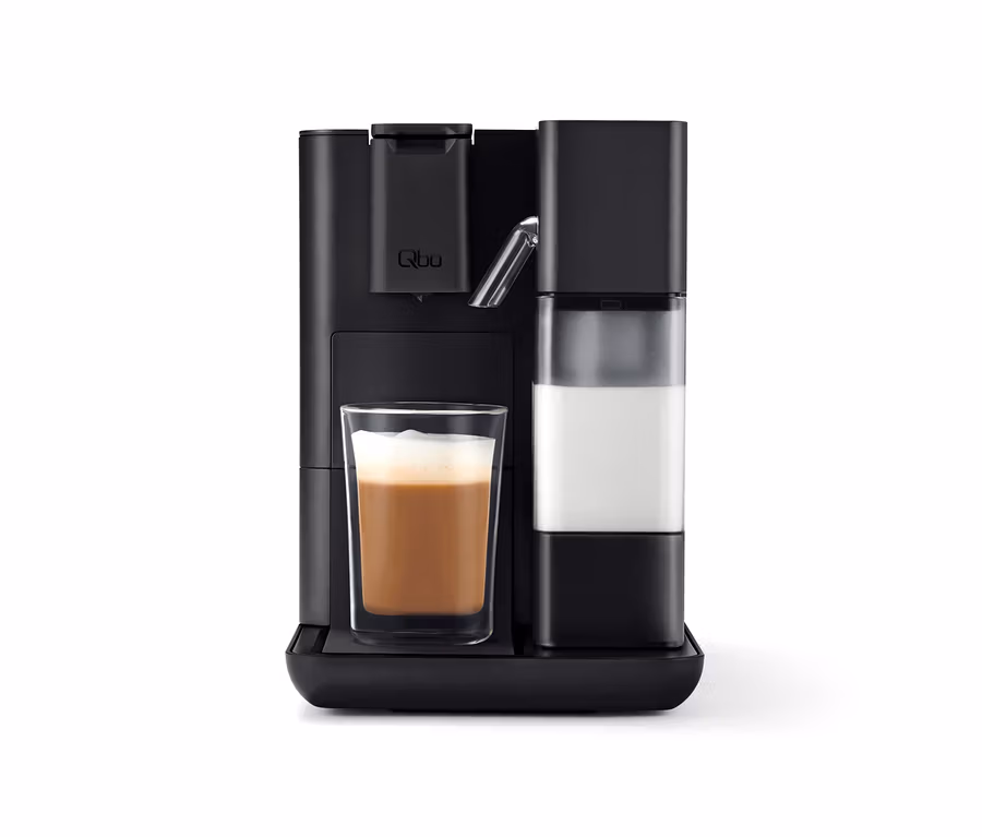 Schwarze Qbo MILK MASTER Velvet Black Kaffeemaschine mit einem Glas Milchkaffee.