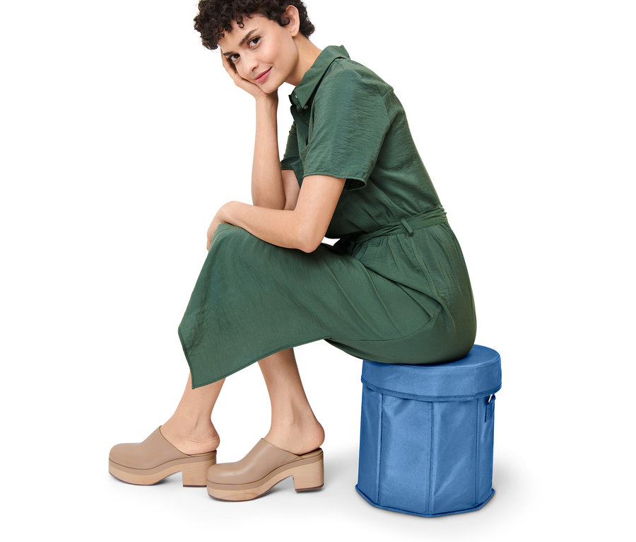 Frau sitzt auf blauer 2-in-1-Kühltasche.