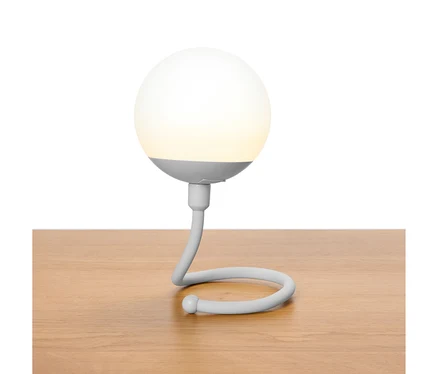 Graue kugelförmige Lampe mit geschwungenem Hals steht auf einem Holztisch.