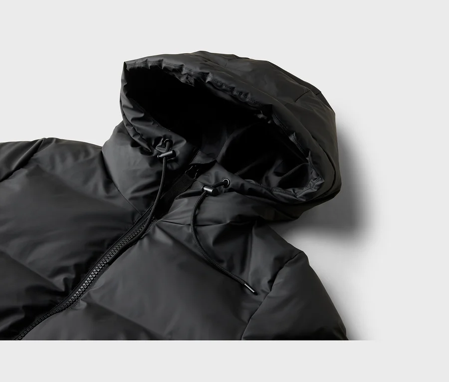 Nahaufnahme des oberen Teils einer schwarzen Steppjacke, die Kapuze mit Kordelzug, einen hohen Kragen und einen teilweise sichtbaren Reißverschluss zeigt.