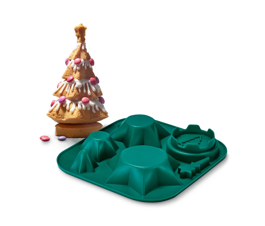 Ein gebackener Weihnachtsbaum steht neben einer grünen Silikonbackform »Weihnachtsbaum«.