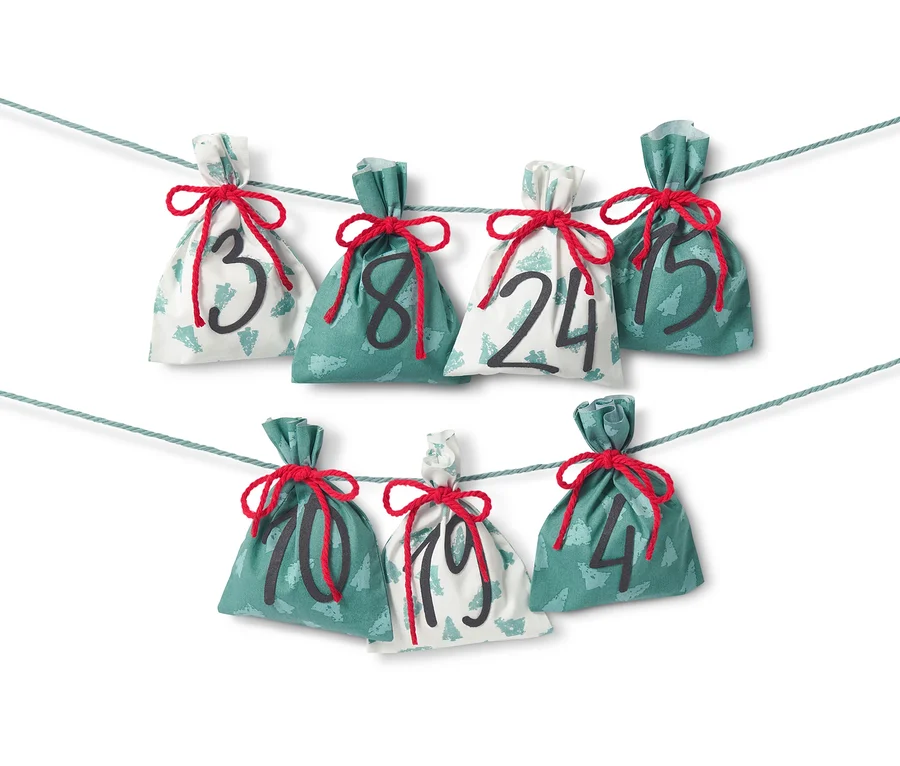 Näh-Set »Stoff-Adventskalender« mit sieben Stoffsäckchen mit den Zahlen 3, 8, 24, 15, 10, 19 und 4, die an einer Schnur aufgehängt sind.