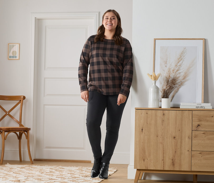 Frau posiert in Jeggings und kariertem Sweatshirt.